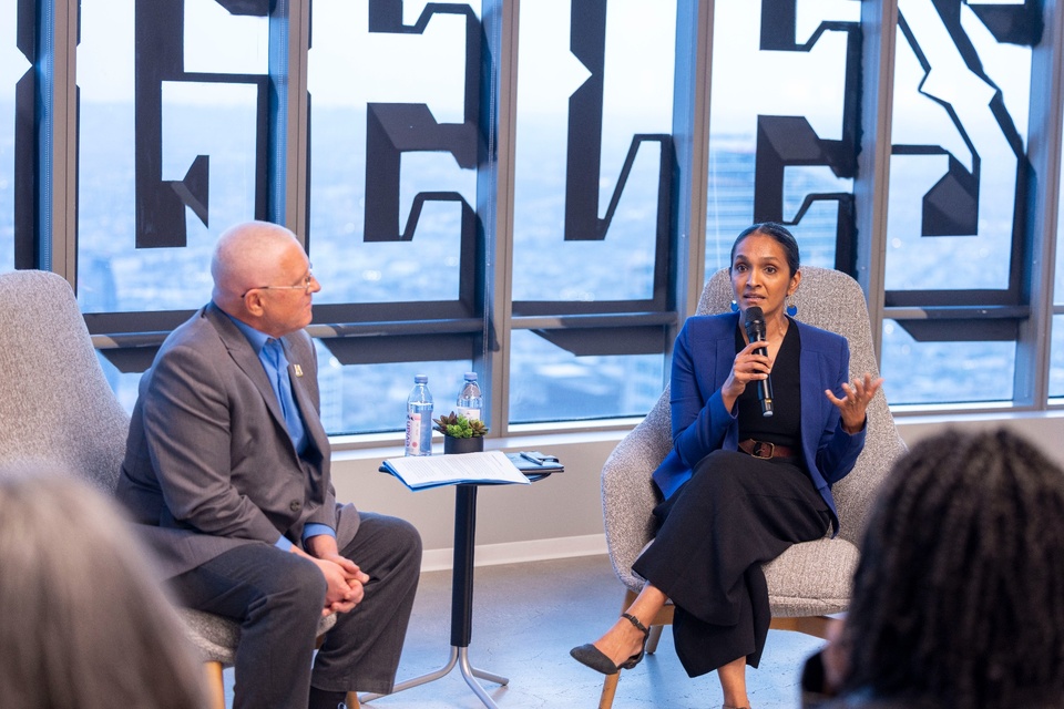 Two panelists engage in a fireside chat during a Cal State LA event, with one speaker addressing the audience while holding a microphone.